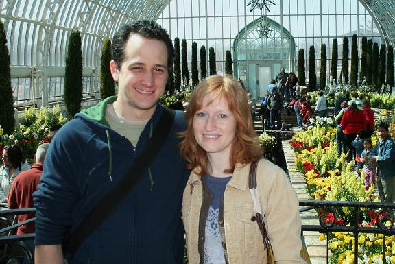A person and person standing in a greenhouse

Description automatically generated